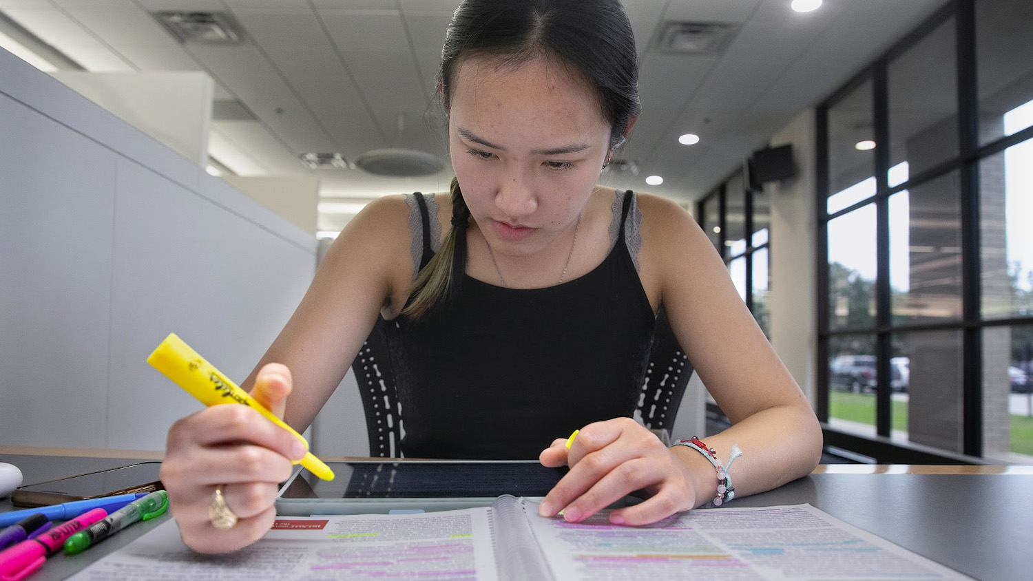 Student studying a textbook while holding a hightlighter